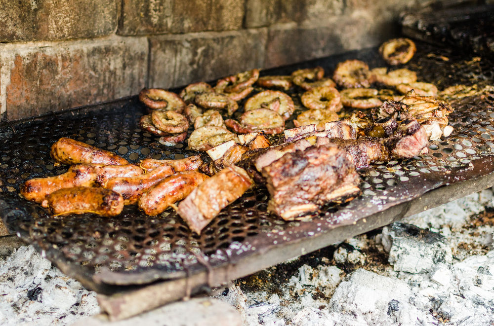 Traditional Argentina asado grilled meat barbecue. Chorizo sausages, ribs, and intestines on a parilla grill.